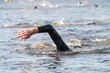 Male participant swims in open water at the start of a triathlon on a lake