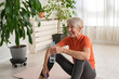 Beautiful senior woman drinking water after exercise. Active senior woman practicing yoga indoors. Exercise for Older Adults
