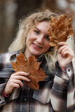 Fototapeta Na drzwi - Portrait of a Woman Holding a Leaf and Smiling at Camera