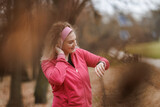 Fototapeta Miasto - Woman Checking Her Smartwatch During Autumn Park Workout