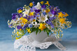 Bouquet of wild spring flowers in a cup, blue muscari, hepatica, pansies, yellow anemones, white bird cherry. Beautiful card