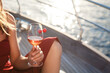 Woman drinking wine on yacht at sea. Summer picnic with wineglass of alcohol-free beverage. Vacation and traveling at sunset. Happy girl relaxing, enjoying holidays. Lifestyle moment. Close up