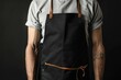 © Fotograf - A man wearing a black apron with a leather strap, suitable for restaurant or kitchen scenes