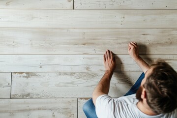 Wall Mural - A man sitting on a wooden floor, versatile image for various concepts