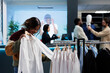© DC Studio - African american woman trying on shirt, checking size and fit while shopping in clothing store. Customer examining apparel while choosing formal outfit in mall fashion boutique