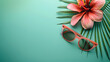 sunglasses and pink flower lay on a green background