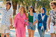 © Minet - A diverse group of tourists, dressed in summer attire, strolls through the tourist city with wide smiles, enjoying their sightseeing adventure