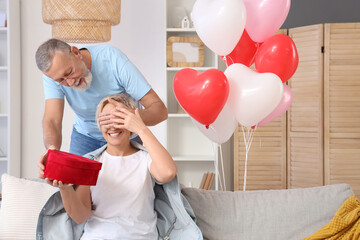 Canvas Print - Mature man greeting his wife with gift at home on Valentine's Day