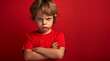 © Enrique - Studio portrait of a very angry and petulant child in a red shirt. Arms folded. Exaggerating and feigning anger