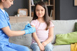 © Pixel-Shot - Doctor pressing gauze on little girl's arm after vaccination at home