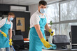 © Pixel-Shot - Male worker of cleaning service disinfecting table in office