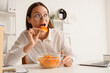 © Pixel-Shot - Young businesswoman eating potato chips at table in office
