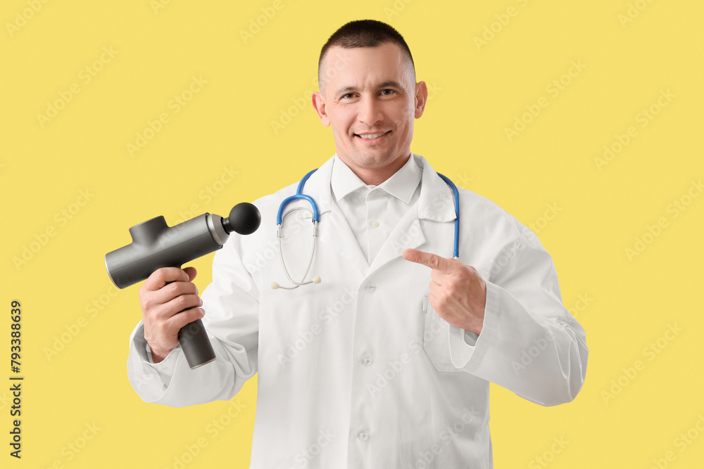 Male doctor pointing at percussive massager on yellow background