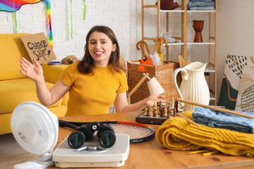 Canvas Print - Young woman with unwanted stuff for garage sale on table in room