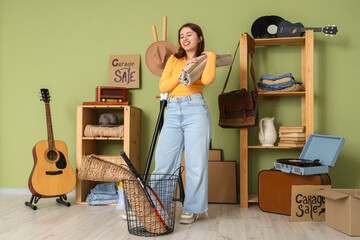 Canvas Print - Young woman with rolled carpet for garage sale in room of unwanted stuff