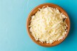 Grated mozzarella cheese in wooden bowl