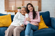 Portrait of Asian senior father sitting on sofa with daughter in house. 