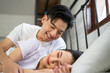 Asian attractive man hugging his girlfriend while lying down on bed. 
