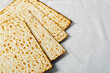 Matzo, an unleavened flatbread integral to Jewish Passover on a textured white surface. The matzo, light and crisp with golden brown spots from baking, symbolizes the Jews hasty exodus from Egypt.