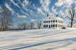 An off-white American classic home, surrounded by a snow-covered landscape under a winter sky.