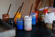 Paints and brushes. Palette with oil paints and gouache set old wood box. Painter vintage workplace ready for drawing closeup. Antique art studio workshop with old brushes & mixed paints on background
