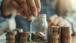 A person is putting coins into a jar. Concept of saving money and being frugal