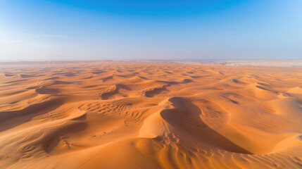 Wall Mural - Aerial view of a vast desert with sand dunes rippling towards the horizon under a clear blue sky