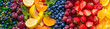 A stunning display of assorted fruits and vegetables arranged in a gradient of colors, resembling a vibrant rainbow, against a grey background with high-key lighting.
