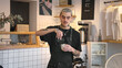 © SERGEI - Handsome barista guy work coffee shop. Tattooed hipster man portrait. Happy male face smile. Joy young adult person look at camera cozy cafe house. Stylish dyed hair waiter make hot tasty drink order.