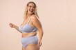© Wavebreak Media - Plus-size young Caucasian model in light blue underwear laughs on a beige background, copy space
