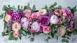 A stunning arrangement of peony pink and purple roses nestled in a box sits elegantly on a white table captured in a top down view with a soft focus background highlighting the lush greens 