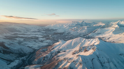 Wall Mural - Aerial view of snow-capped mountains shining in the morning light on a quiet winter day