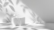 © MUCHIB - White porous cube, square podium with leaves and shadows on a white gray background. Conceptual scene, showcase for a new product, presentation, sale, advertisement, banner, cosmetics.