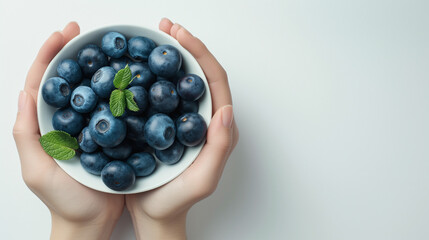 Sticker - Feminine hands holding a bowl with blueberries on a white table top view space on the right