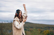 © SHOTPRIME STUDIO - Mountain Melodies: A Joyful Woman, immersed in Nature's Rhythms, Dances Freely to Springtime Beats while Walking through an Adventure Trip, enjoying the Freedom of Music and Travel. Her Hipster
