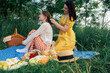 Two young women on a blue blanket outdoors on a picnic