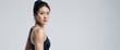 © Roman - Young fit Asian sexy woman wearing black sportswear standing isolated on a gray background. Studio portrait of a healthy muscular female.