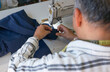 © Arianne - Man sewing a hem of pants with sewing machine