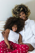 © BUDDHA - Image of african american woman and her little daughter hugging in bedroom
