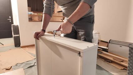 Wall Mural - Man working and assembling furniture in a new apartment.