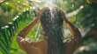 
A young woman joyfully swims beneath a waterfall, gently cleansing her hair
