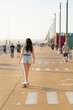 A woman is skateboarding down a sidewalk