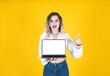 Excited young caucasian blonde curly hair woman holding empty blank white screen laptop mock up show thumb up like approve gesture isolated on yellow studio background, copy space.