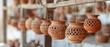 clay pots with cut out patterns hanging from metal bars, light background, clay and terracotta
