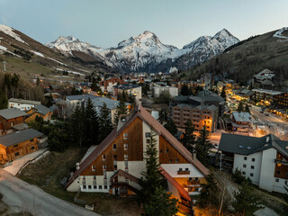 Wall Mural - Town in the alps mountains during sunset.Aerial drone photo Blue Hour French alps in winter, Rhone Alpes in France Europe. Les deux alpes village in spring time.Winter French Alpes town from drone