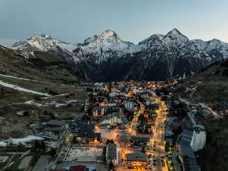 Wall Mural - Town in the alps mountains during sunset.Aerial drone photo Blue Hour French alps in winter, Rhone Alpes in France Europe. Les deux alpes village in spring time.Winter French Alpes town from drone