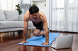 Athletic and sporty man doing mountain climber on fitness mat during online body workout exercise session for fit physique and healthy sport lifestyle at home. Gaiety home exercise workout training.