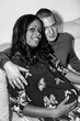 Multinational couple sitting on the couch with her pregnant