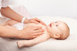 Gentle baby chest massage by a caregiver on a soft white blanket