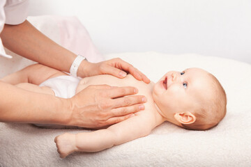 Wall Mural - Gentle baby chest massage by a caregiver on a soft white blanket